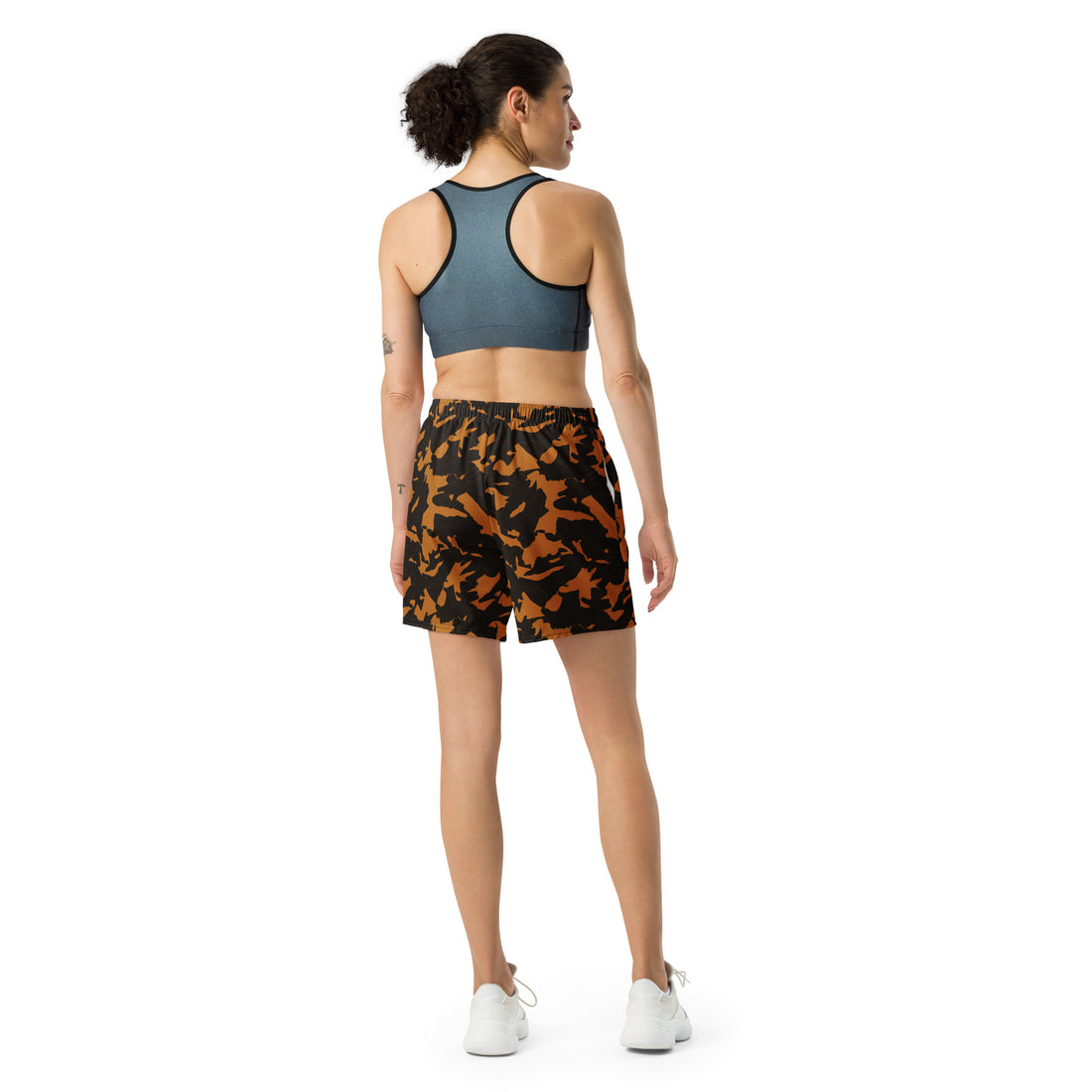 Camo Print Unisex Athletic Long Shorts in black and orange worn by a model