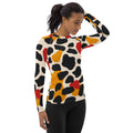 Women's long-sleeve rash guard featuring a colorful abstract pattern in reds, yellows, and blacks on a cream background.