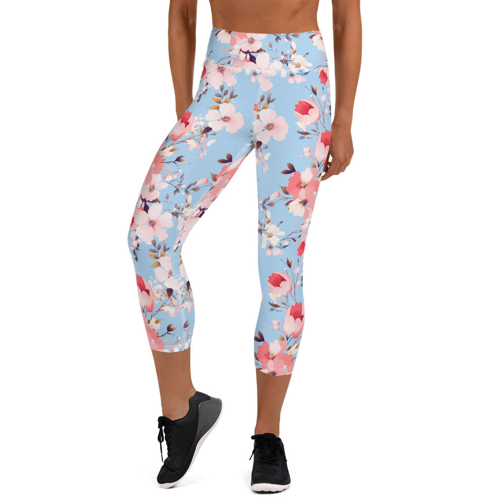 Woman wearing yoga capri leggings with blue background and pink floral design, featuring high waistband and mid-calf length.