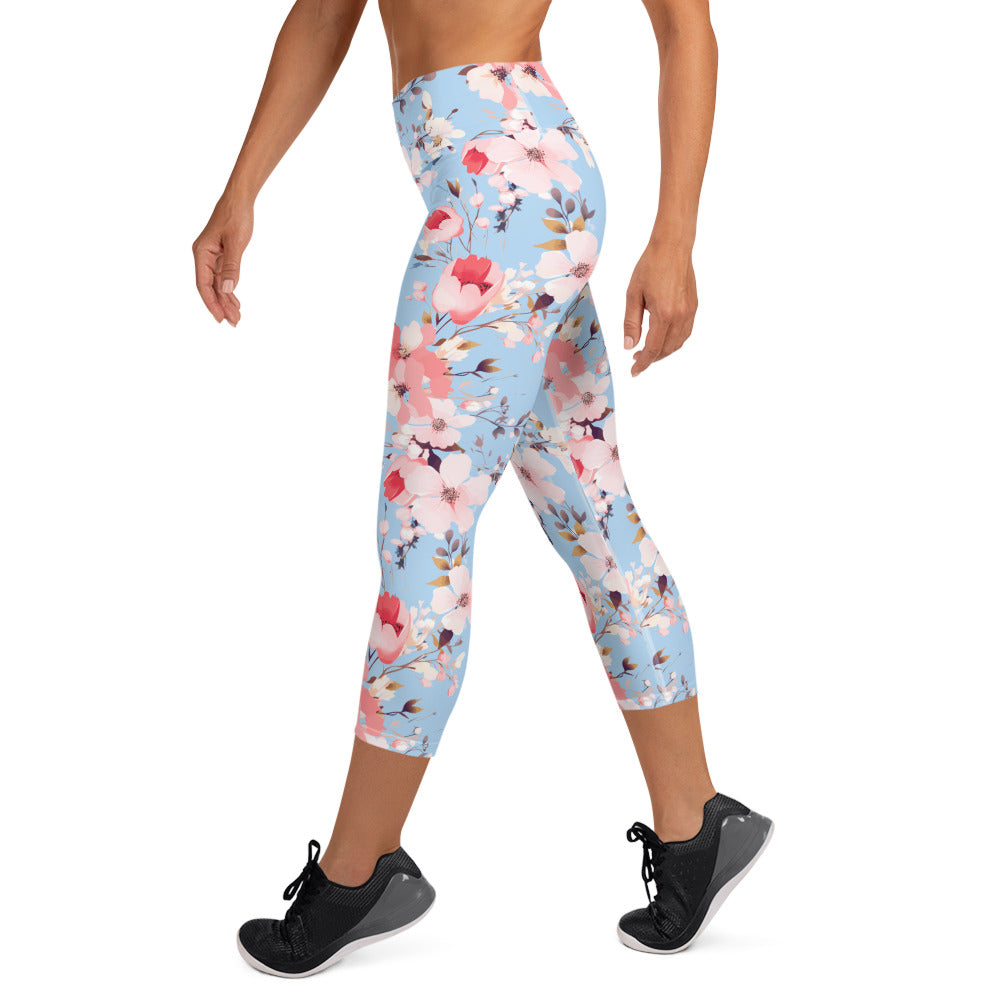 Woman wearing yoga capri leggings with blue background and pink floral design, featuring high waistband and mid-calf length.