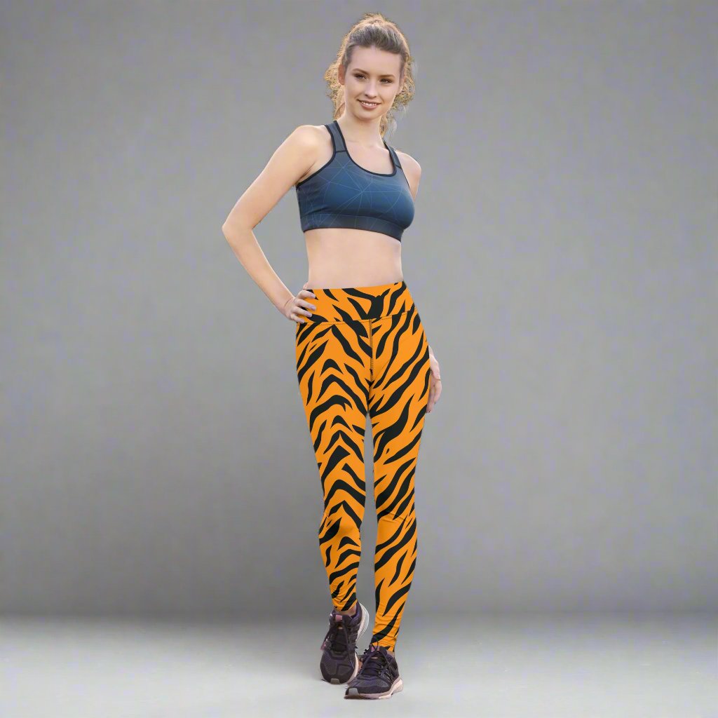 Tiger print yoga leggings in vibrant orange and black on model in outdoor setting.