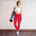 Red Halloween bat yoga leggings with black bat print on a woman holding a yoga mat.