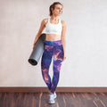 Cosmic yoga leggings in mystical colors, perfect for Halloween season, worn by a woman holding a yoga mat.