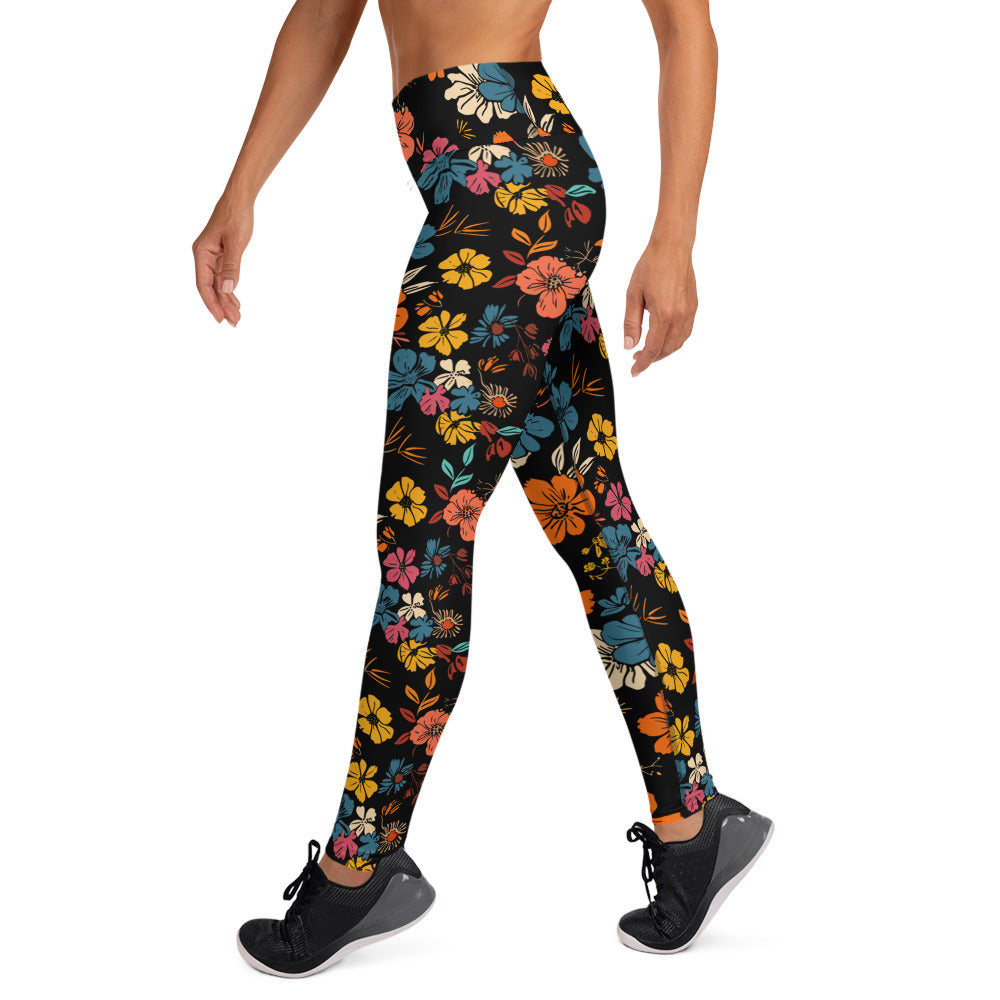 Vibrant floral yoga leggings with orange, teal, yellow, and pink flowers on a black background, displaying a raised waistband.