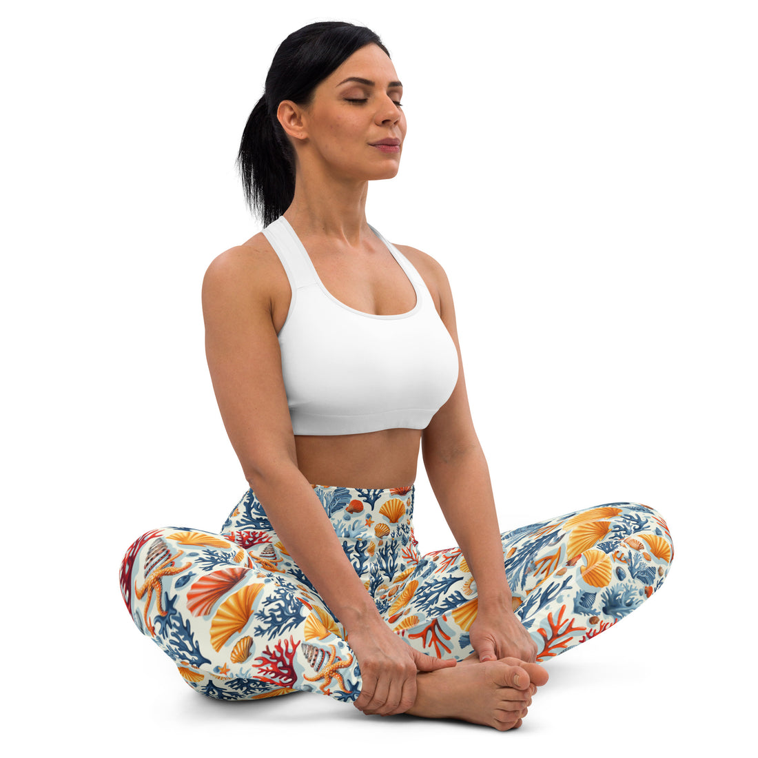 Woman wearing yoga leggings with vibrant coral reef and seashell patterns in teal, orange, and cream, performing a yoga pose.