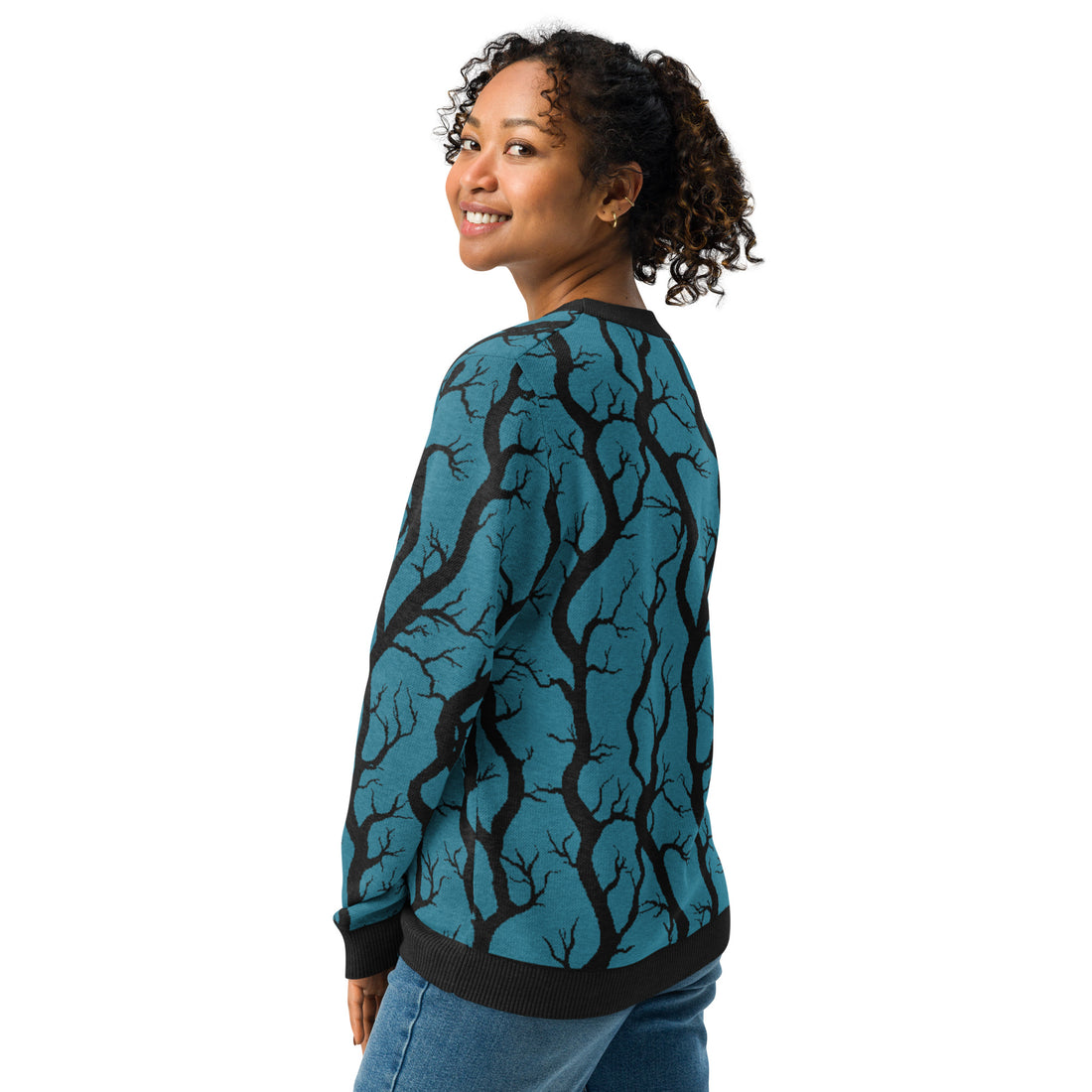 Woman wearing a teal and black tree branch patterned knitted sweater, perfect for fall and winter fashion.