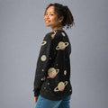 A woman wearing a black knit sweater showcasing Saturn and star designs, perfect for fall and winter fashion.