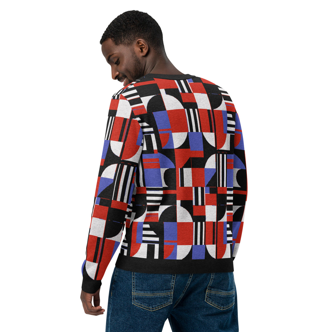 Woman wearing a geometric patchwork knitted crew neck sweater featuring vibrant red, black, and blue patterns.