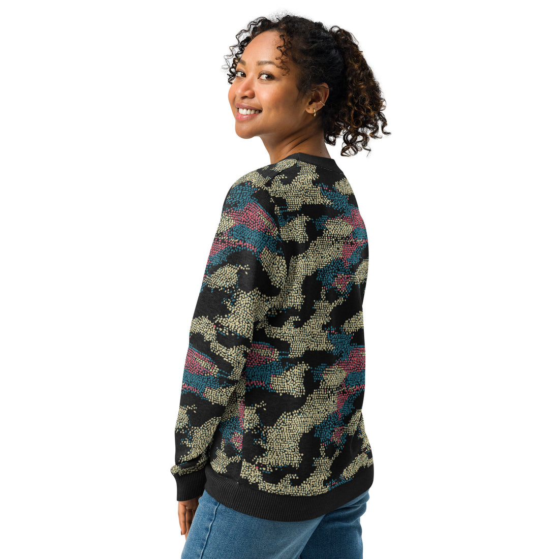 Knitted sweater with abstract art design in rich blues and deep pinks on black, modeled by woman enjoying comfortable wear.