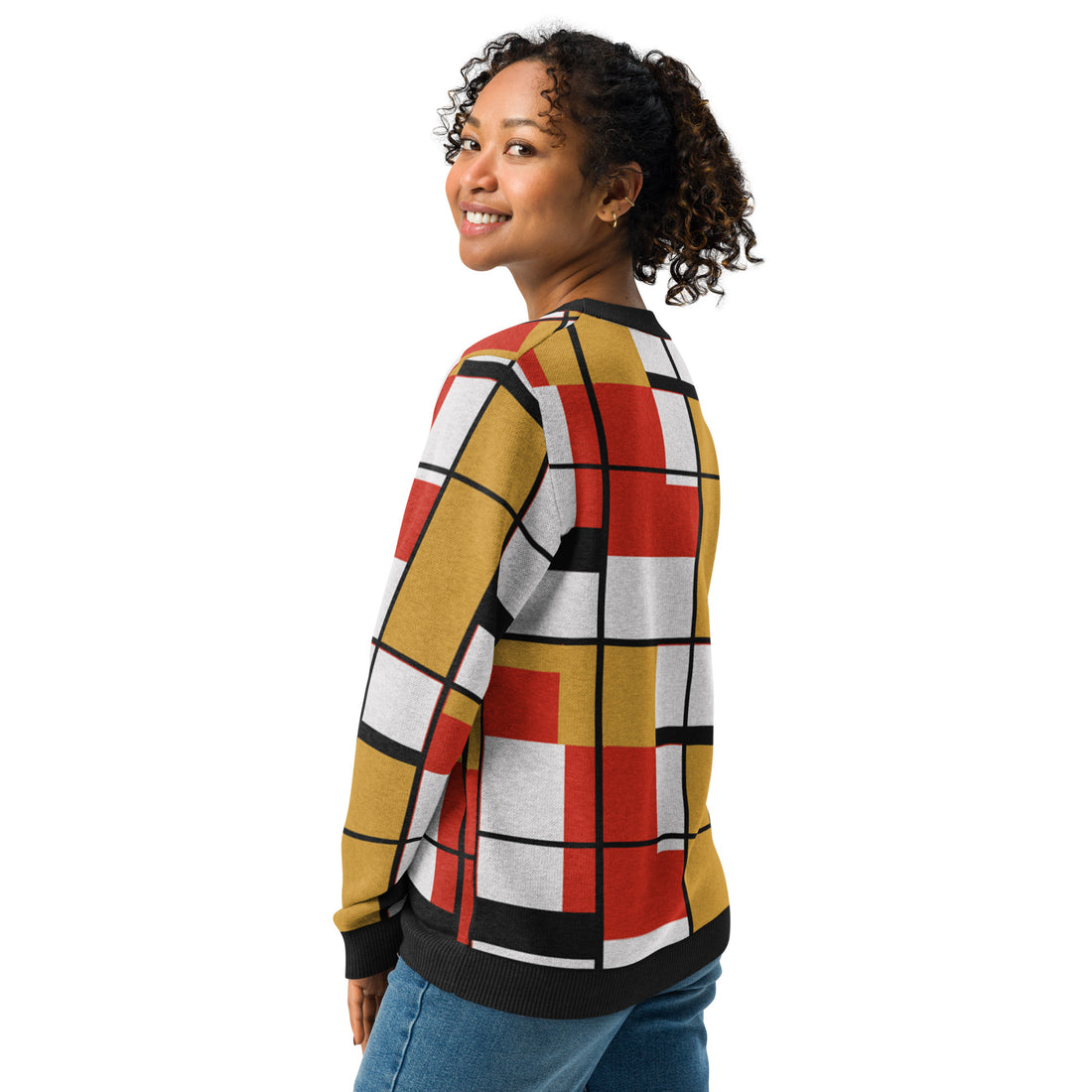 Woman wearing a geometric patchwork knitted sweater with red, mustard, and black patterns, perfect for fall fashion.