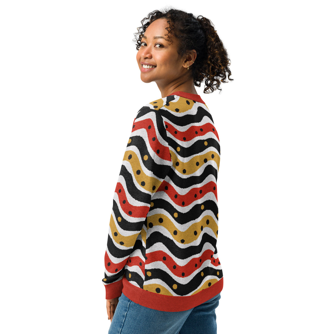 Woman wearing a knitted sweater with wavy polka dot pattern in red, black, and gold, featuring a crew neck design