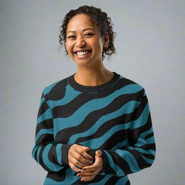 Woman wearing a teal and black zebra striped knitted sweater, showcasing its unique design ideal for fall fashion.