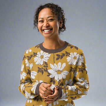 Knitted sweater featuring a brown and white daisy floral pattern, worn by a smiling woman, epitomizing fall fashion.