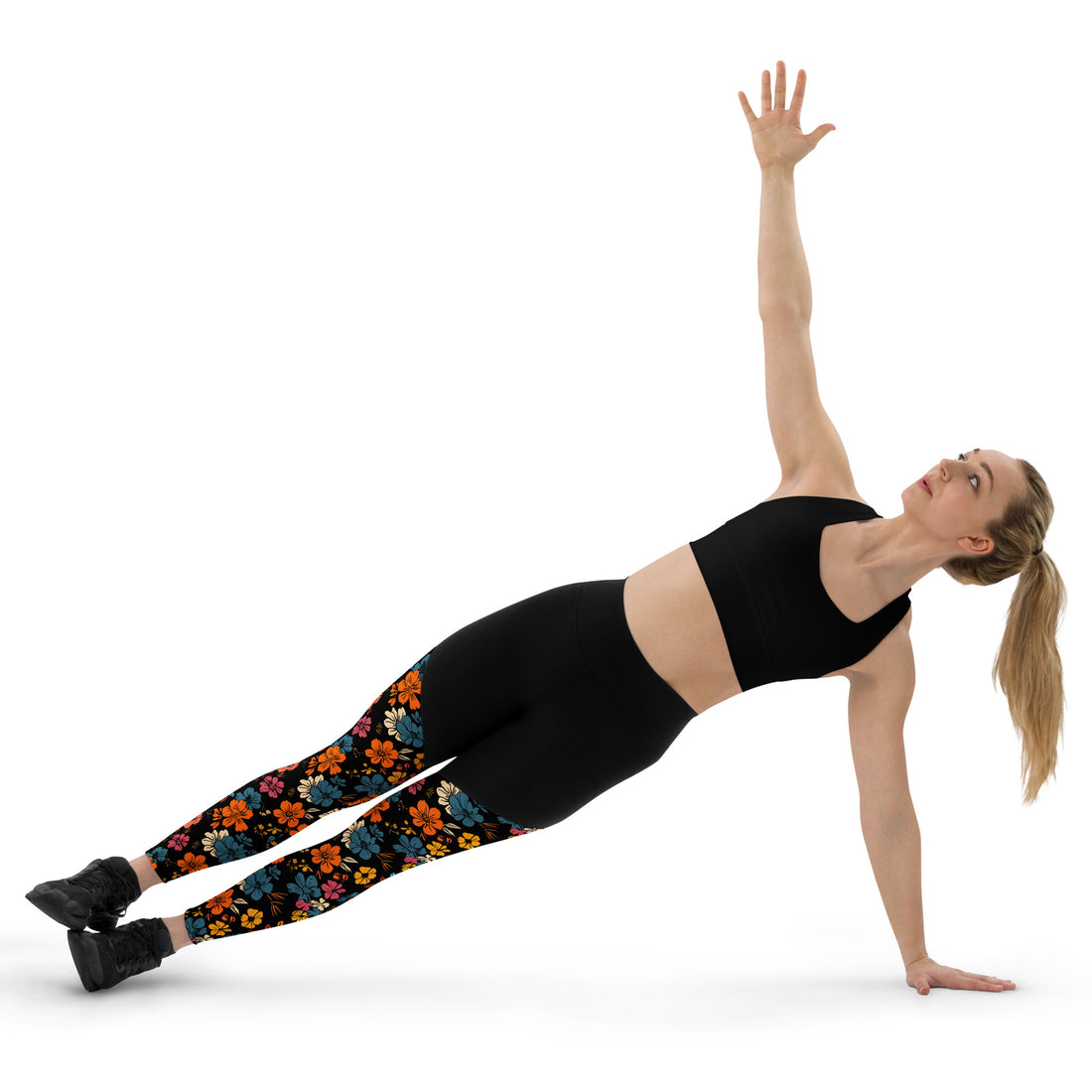 Woman wearing black high-waisted leggings featuring vibrant floral patterns, performing a side plank.