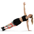 Woman in black sports bra and Floral Fusion Compression Leggings with vibrant blossom design, performing a side plank pose. Winter fashion activewear.