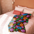 Brightly colored sherpa blanket with blue, green, pink, orange circles on black background, draped on a bed.