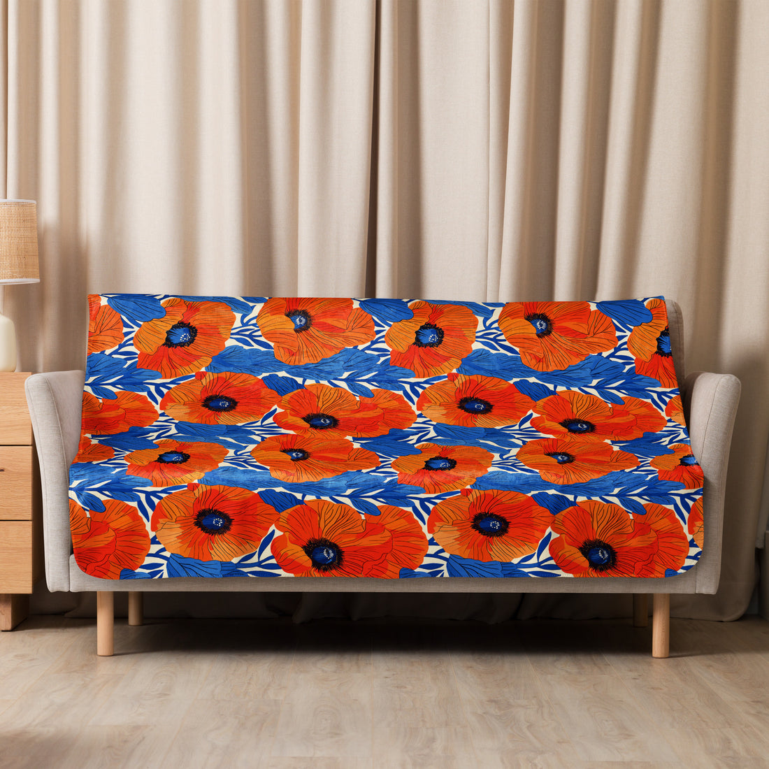 Vibrant orange poppy floral design sherpa blanket on beige sofa with blue accents.