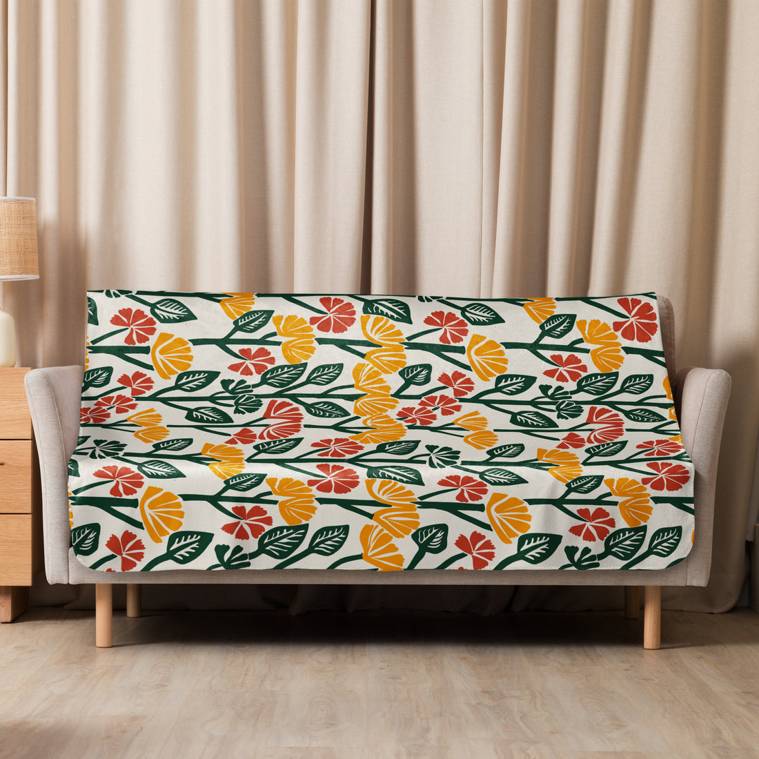 Sherpa blanket with vibrant floral pattern featuring mustard yellow, deep green, and soft red hues, draped over a sofa.