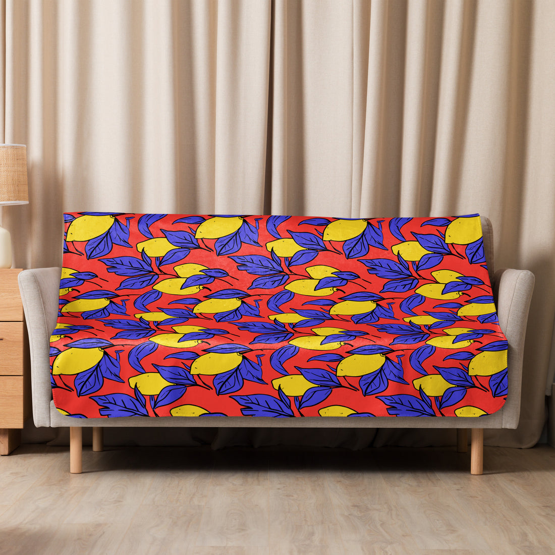 Sherpa blanket with vibrant yellow lemons and blue leaves on a red background draped over a couch, adding a bold statement to a cozy setting.