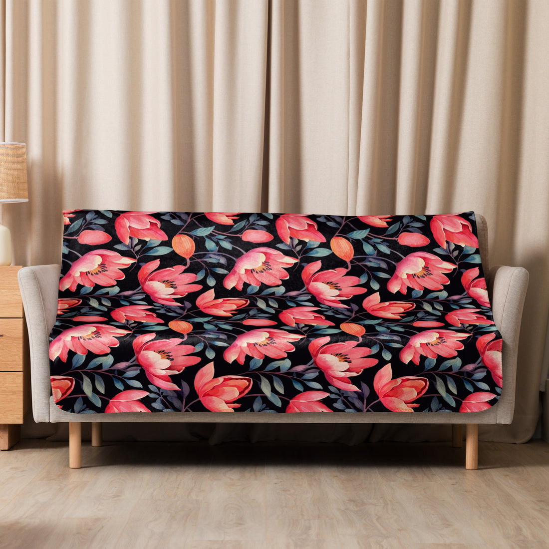 Black Sherpa blanket with vivid poppy floral design in shades of red and coral, draped over a couch in a cozy room setting – perfect for fall and winter aesthetics.