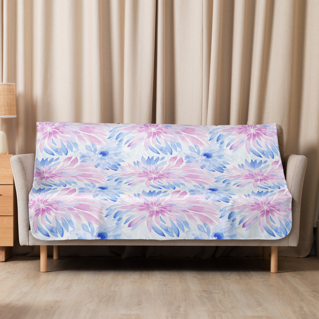 A sherpa blanket featuring a pastel floral design in pink and blue hues, draped elegantly over a sofa.