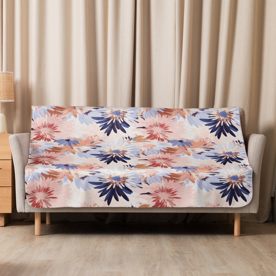 Floral sherpa blanket in shades of navy, blush, and beige draped over a couch, showcasing intricate winter designs.