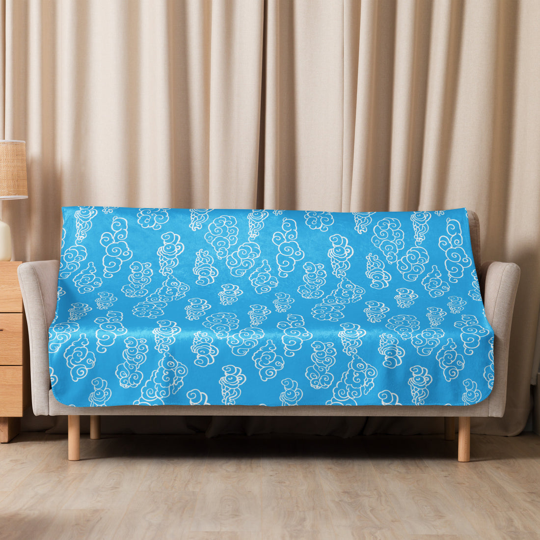 Turquoise sherpa blanket with intricate swirl pattern, draped over a couch, showcasing cozy and elegant design.