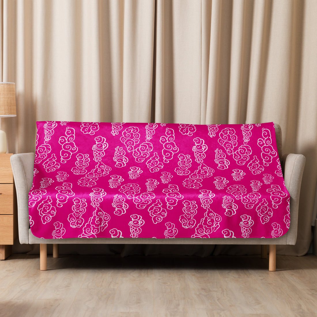 Fuchsia-colored sherpa blanket with intricate swirl designs draped over a sofa.