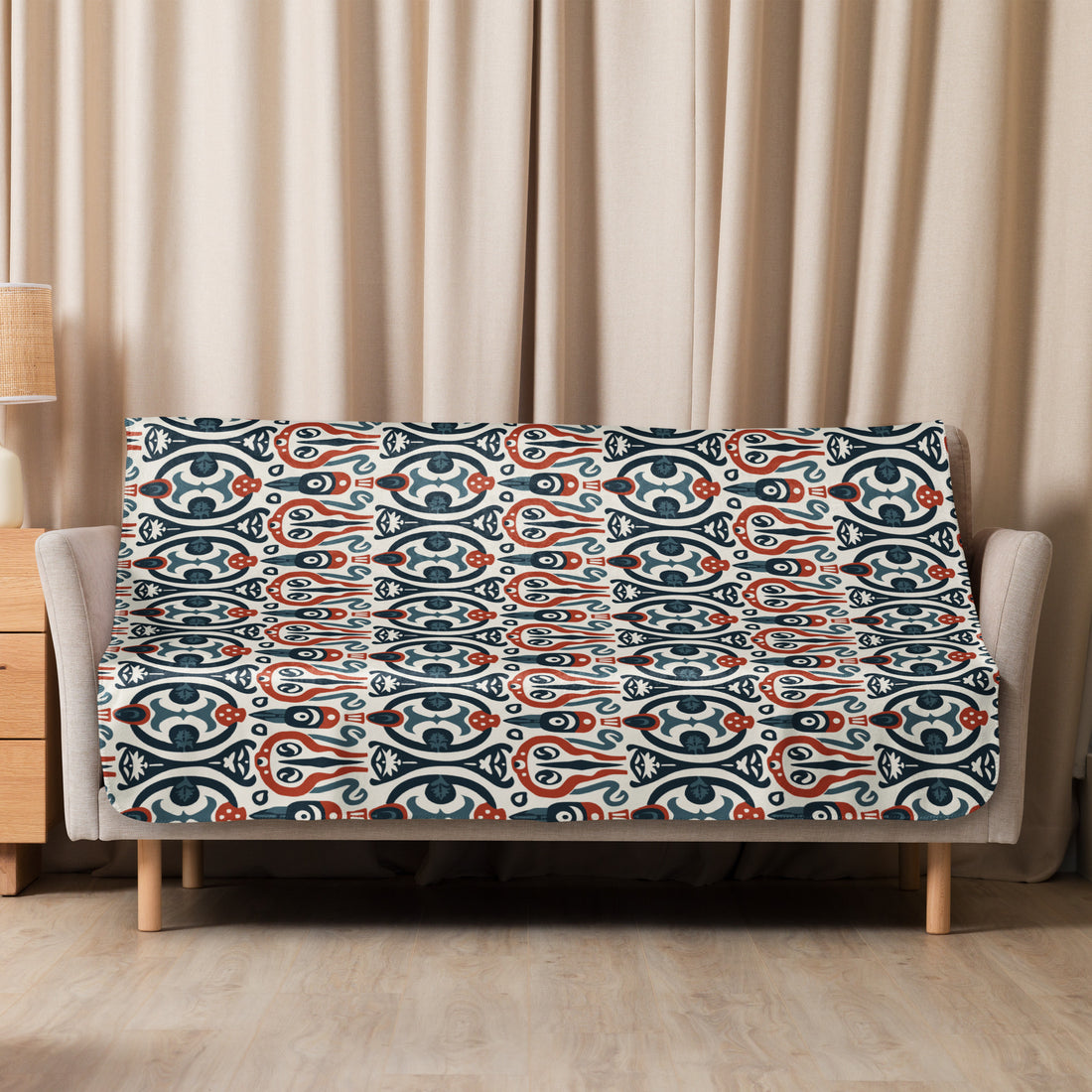 Cozy sofa with Nordic Whimsy Sherpa Blanket draped over, showcasing a unique blue and red winter motif design.