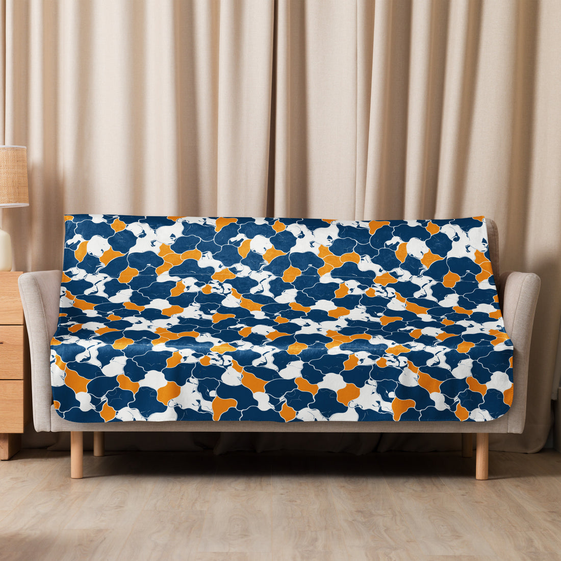 Navy, orange, and white kaleidoscope patterned sherpa blanket on a sofa, showcasing vibrant winter design.