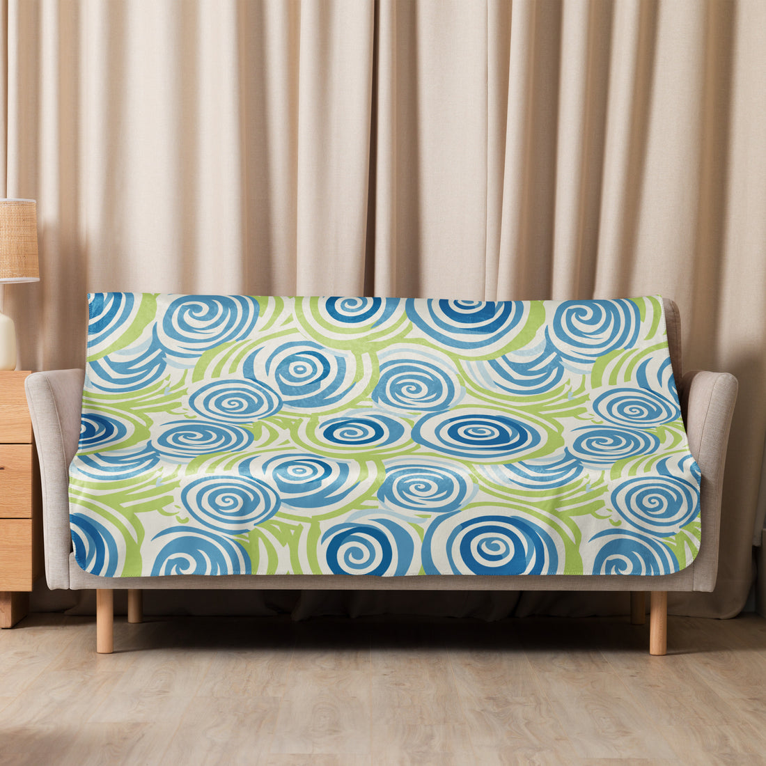 Blue swirl pattern sherpa blanket with vibrant spiral design on soft fabric, draped elegantly over a sofa.