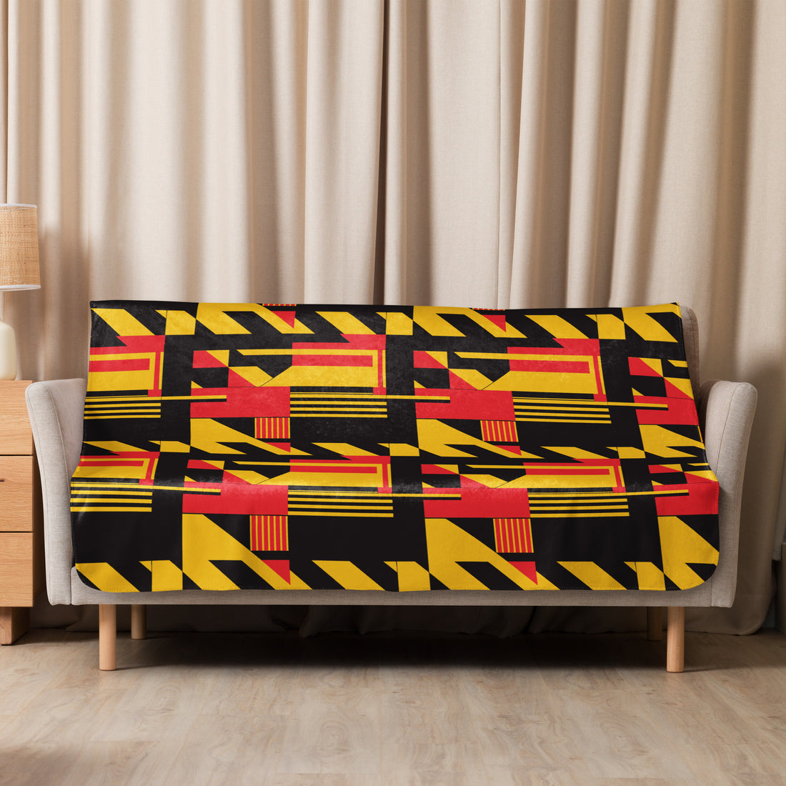 A plush red and yellow geometric patterned sherpa blanket draped over a sofa, with bold and vibrant designs, perfect for cozy winter evenings.