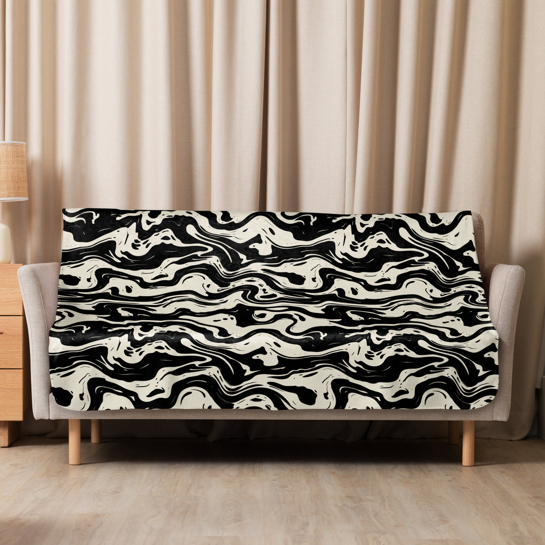 Cozy sherpa blanket with black and cream marbled design draped over a sofa in a warm, inviting room setting.