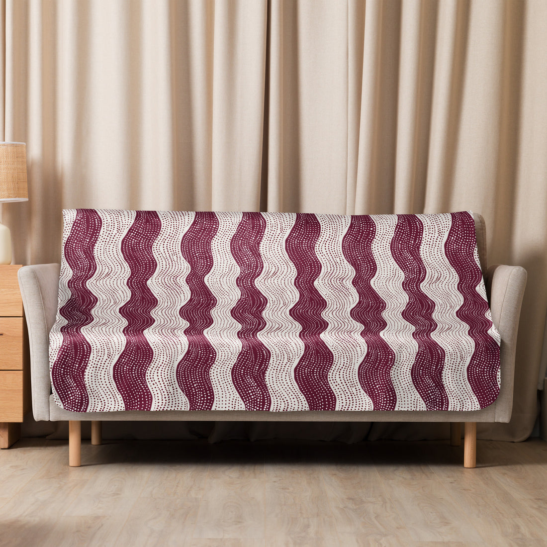 Burgundy wave patterned sherpa blanket draped over a couch, featuring soft and cozy knitted texture ideal for winter comfort.