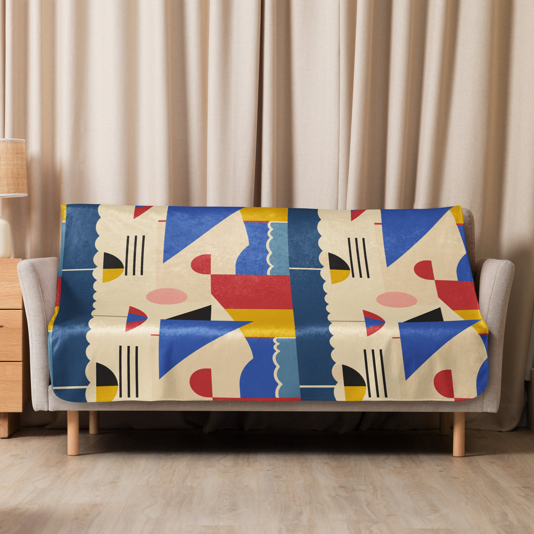 Sherpa blanket draped on a couch with an abstract geometric pattern in blue, red, yellow, and cream colors, adding a modern artistic touch.