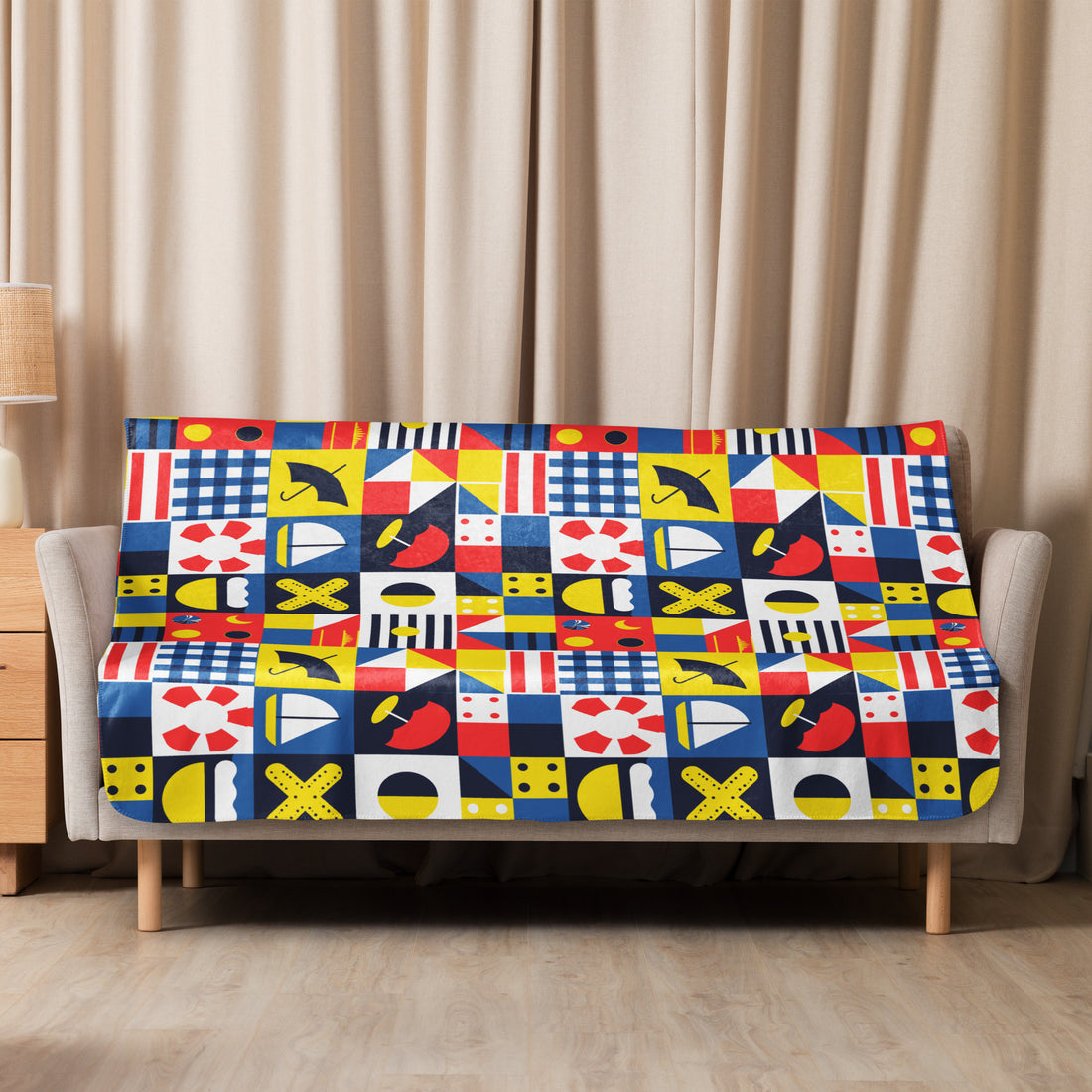 Sherpa blanket with vibrant nautical-themed pattern in red, blue, yellow, and white, styled in a cozy living room.