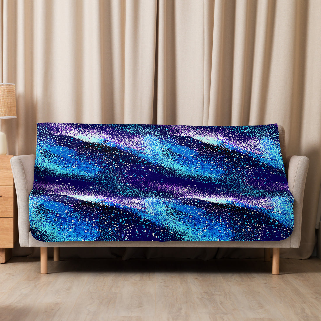 Starry Night Sherpa Blanket draped over sofa showing galaxy-inspired design with blue and purple hues, evoking a cosmic winter night.