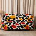 Sherpa blanket with vibrant leopard print design featuring red, yellow, and black abstract patterns draped over a couch.