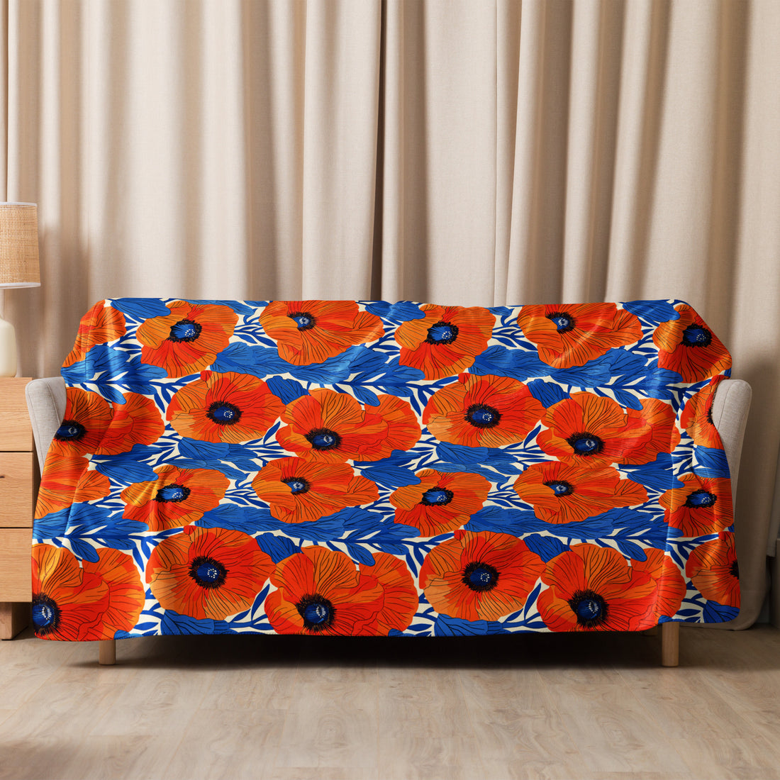 Vibrant orange poppy floral design sherpa blanket on beige sofa with blue accents.