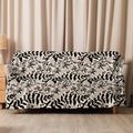 Sherpa blanket with intricate black floral patterns on a beige background, draped over a sofa, embodying elegance and warmth.