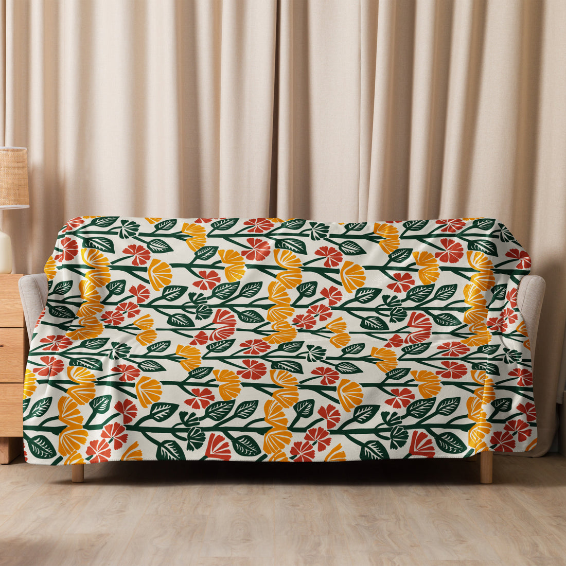 Sherpa blanket with vibrant floral pattern featuring mustard yellow, deep green, and soft red hues, draped over a sofa.