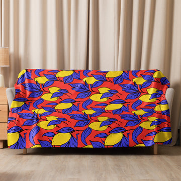 Sherpa blanket with vibrant yellow lemons and blue leaves on a red background draped over a couch, adding a bold statement to a cozy setting.