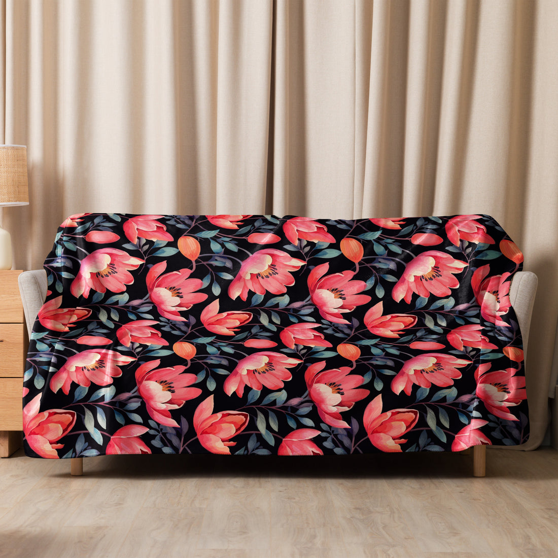 Black Sherpa blanket with vivid poppy floral design in shades of red and coral, draped over a couch in a cozy room setting – perfect for fall and winter aesthetics.