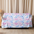 A sherpa blanket featuring a pastel floral design in pink and blue hues, draped elegantly over a sofa.