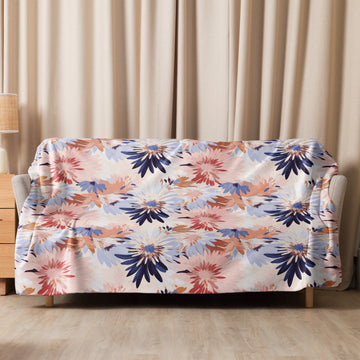 Floral sherpa blanket in shades of navy, blush, and beige draped over a couch, showcasing intricate winter designs.