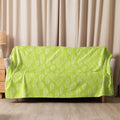 Vibrant green swirl sherpa blanket draped over a sofa, showcasing unique embroidered patterns.