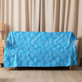 Turquoise sherpa blanket with intricate swirl pattern, draped over a couch, showcasing cozy and elegant design.