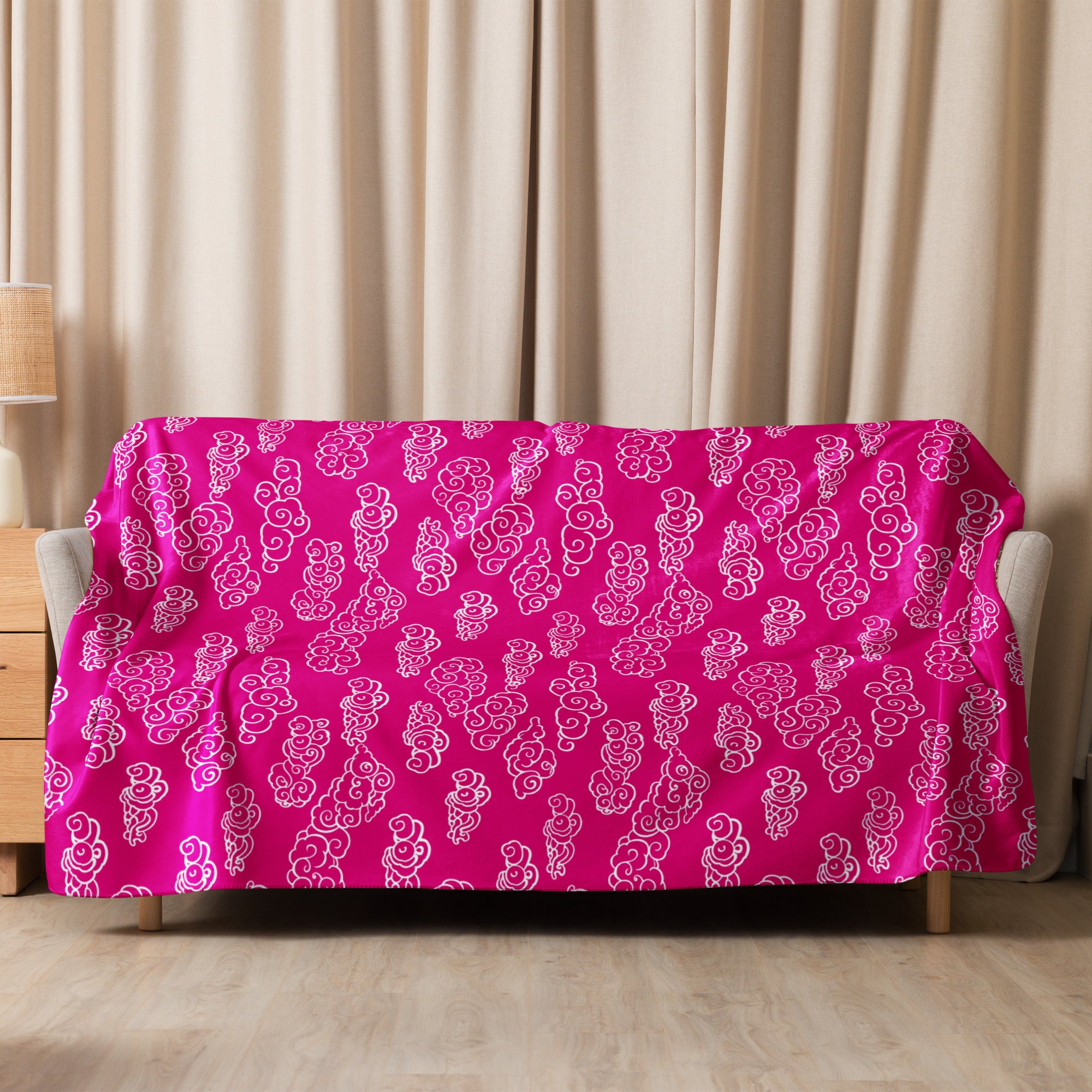 Fuchsia-colored sherpa blanket with intricate swirl designs draped over a sofa.