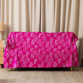 Fuchsia-colored sherpa blanket with intricate swirl designs draped over a sofa.