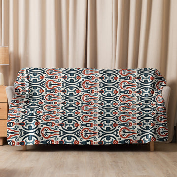 Cozy sofa with Nordic Whimsy Sherpa Blanket draped over, showcasing a unique blue and red winter motif design.